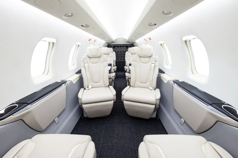 View of the aircraft's interior cabin with white leather seats and a cargo net.