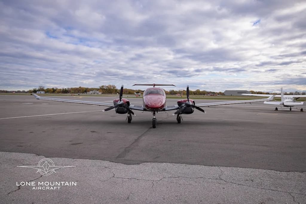 A red and grey Diamond DA62 aircraft with registration C-FCRQ viewed head-on on an airfield.