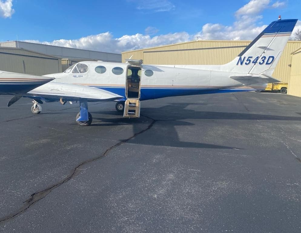 Side view of the Twin Cessna aircraft, registration N543D, with the cabin door open.