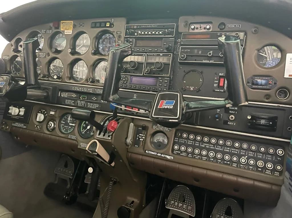 A close-up view of the Piper aircraft's instrument panel, showing gauges, radios, and control yokes.