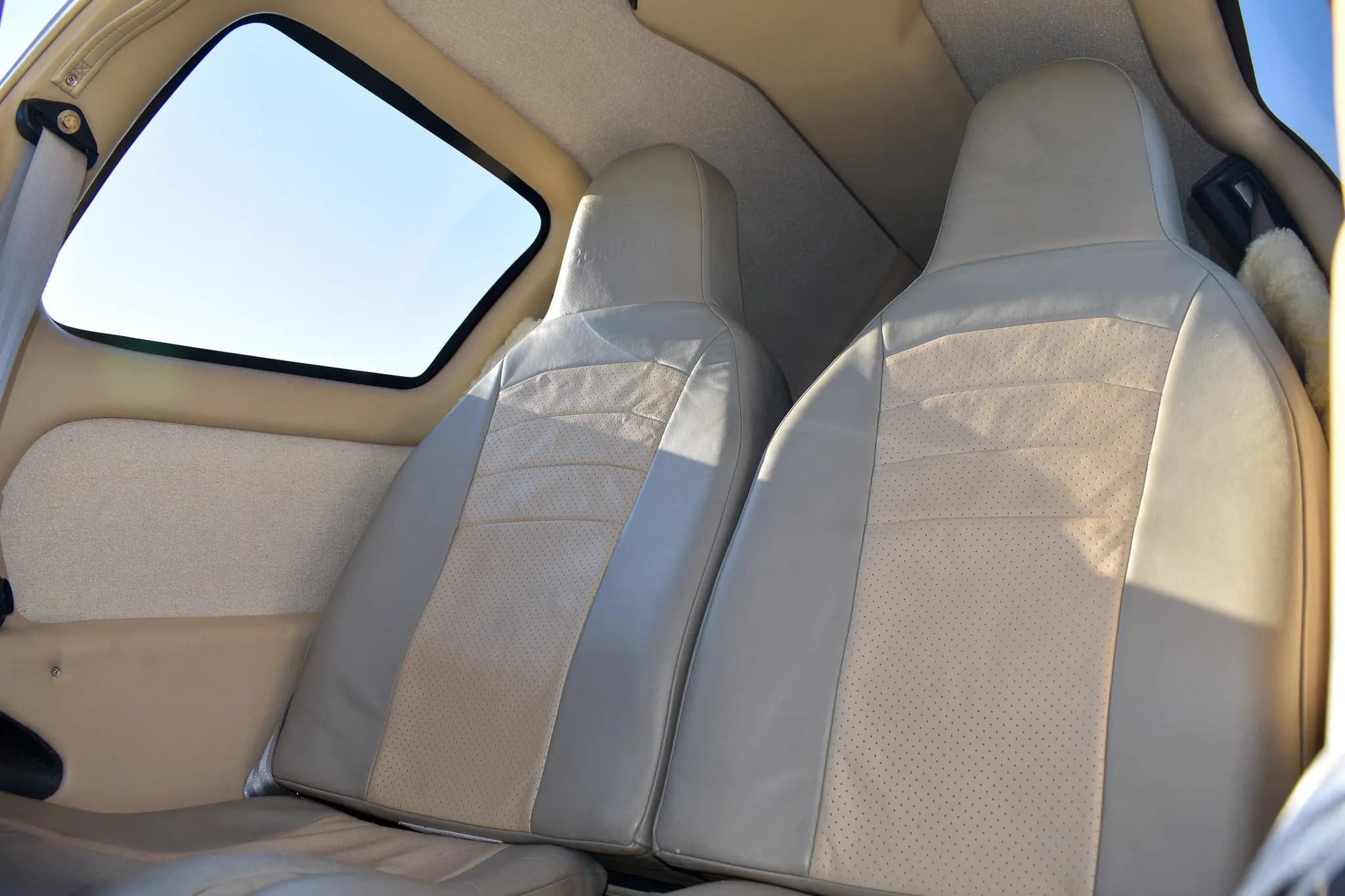 The light-colored leather and fabric front seats in the aircraft cabin.