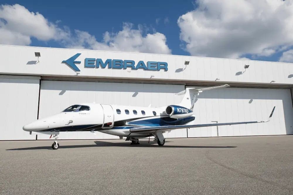 Embraer Phenom 300E aircraft N787AD parked in front of an Embraer hangar.