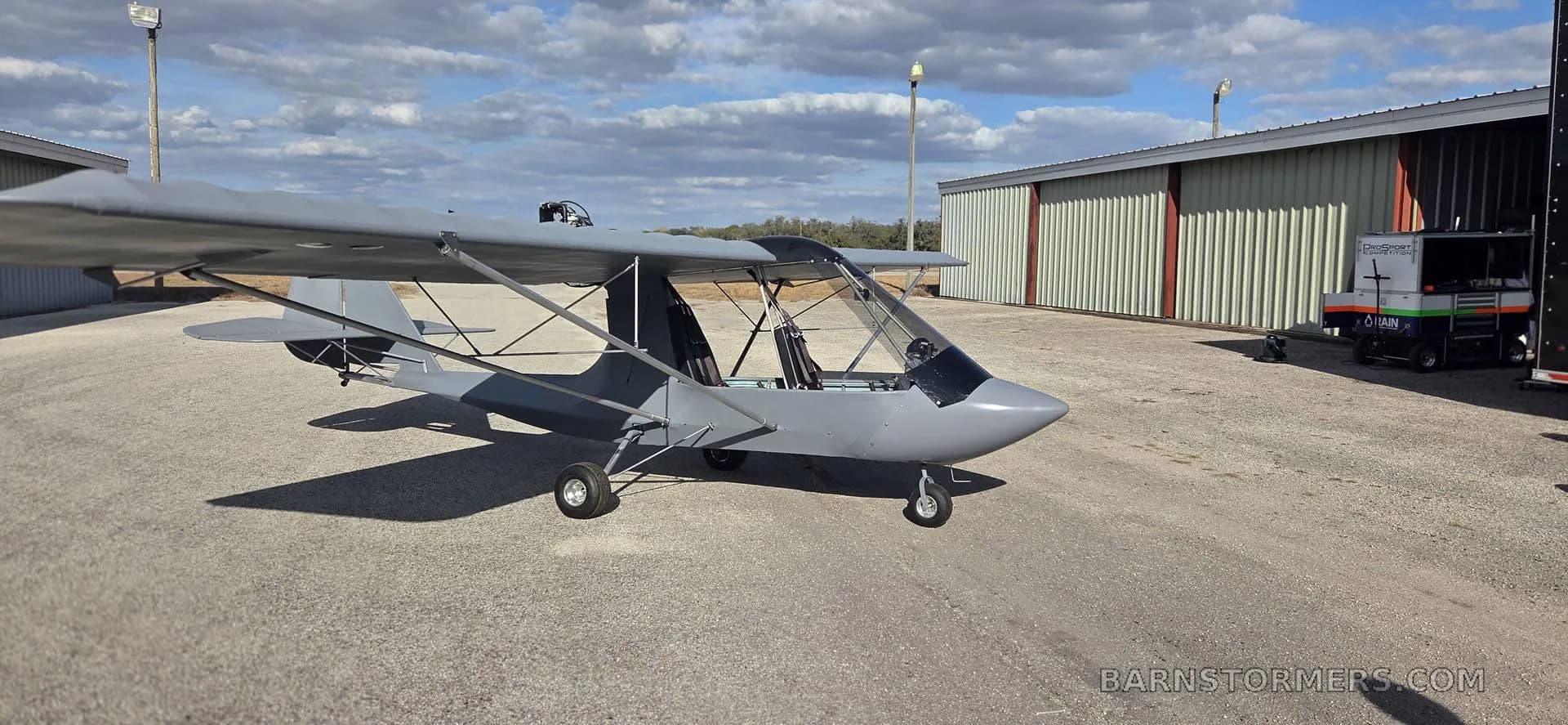 A gray aircraft positioned near hangars.