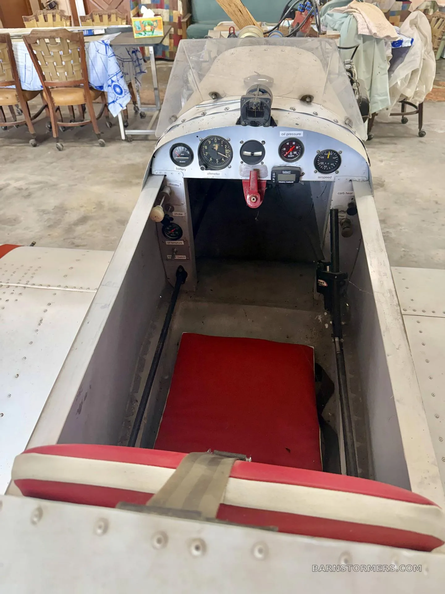 An overhead view into the open cockpit of an experimental aircraft, showing the red seat and basic instrument panel.