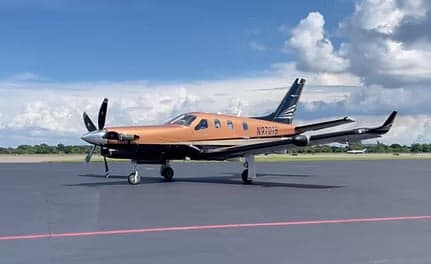 Pilatus PC-12 aircraft N970TB on the tarmac with a copper and black paint scheme.