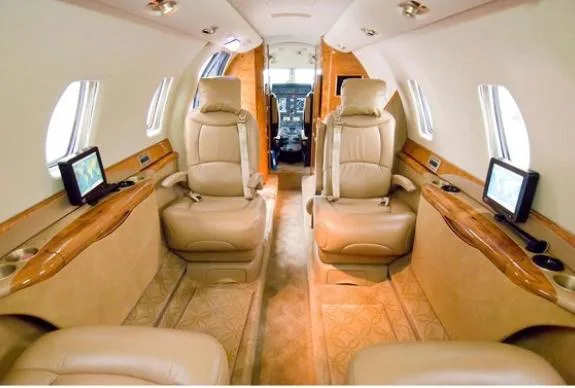 The interior of the aircraft features tan leather seats and wood trim.