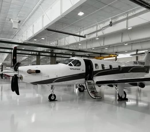 Pilatus PC-12 with open door in a hangar.