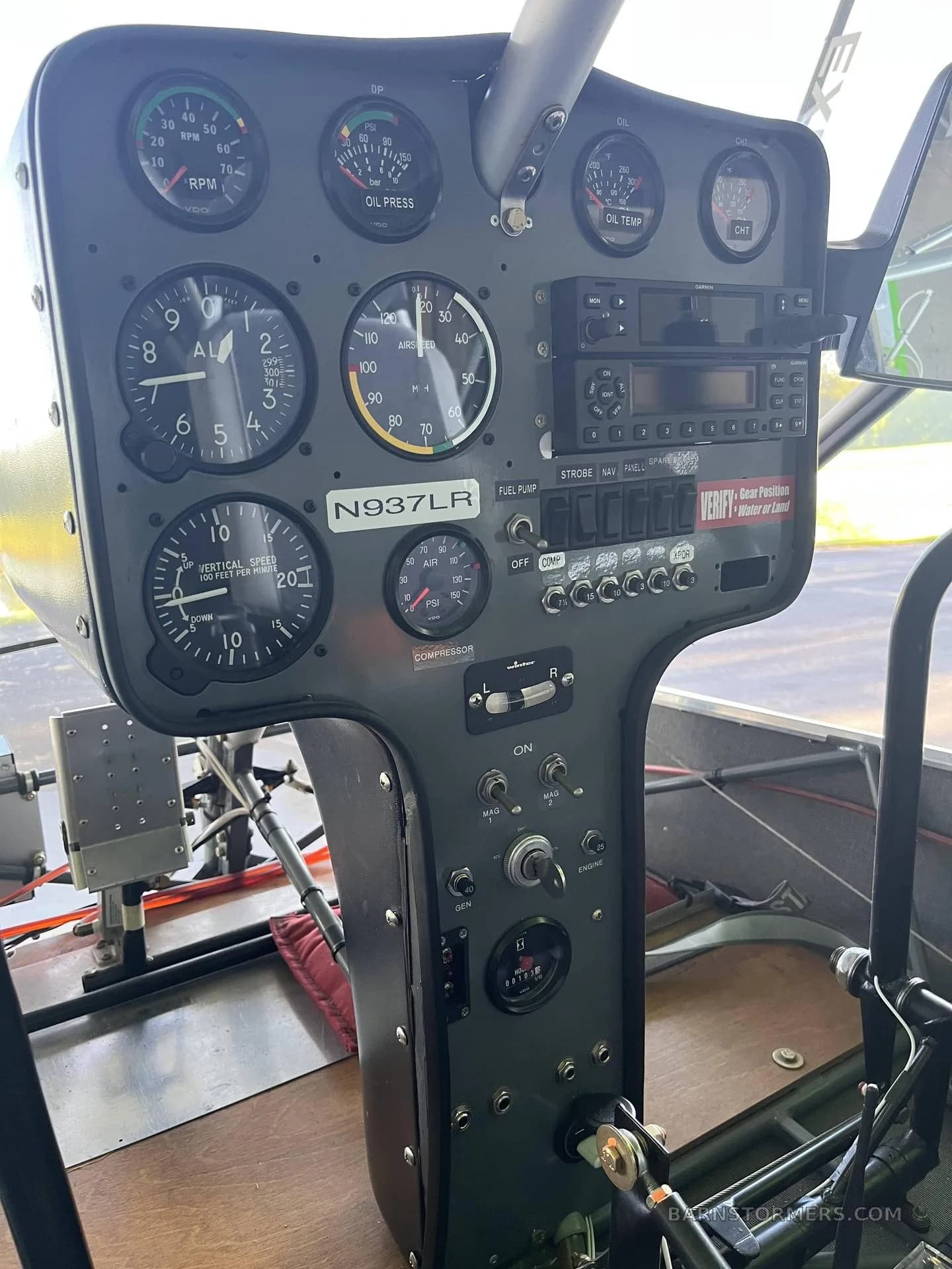 A close-up view of the instrument panel of a green ultralight aircraft, showing various gauges, switches, and a radio.