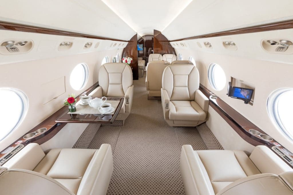 Interior view of a private jet cabin with leather seats and a small table.
