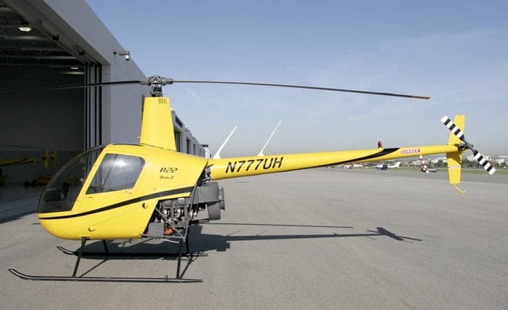 Engine compartment of a yellow Robinson R22 helicopter with registration N777UH.