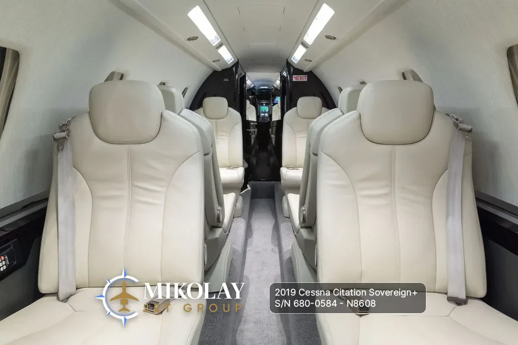 A close-up view of the light-colored leather seats in the aircraft cabin, looking towards the front.