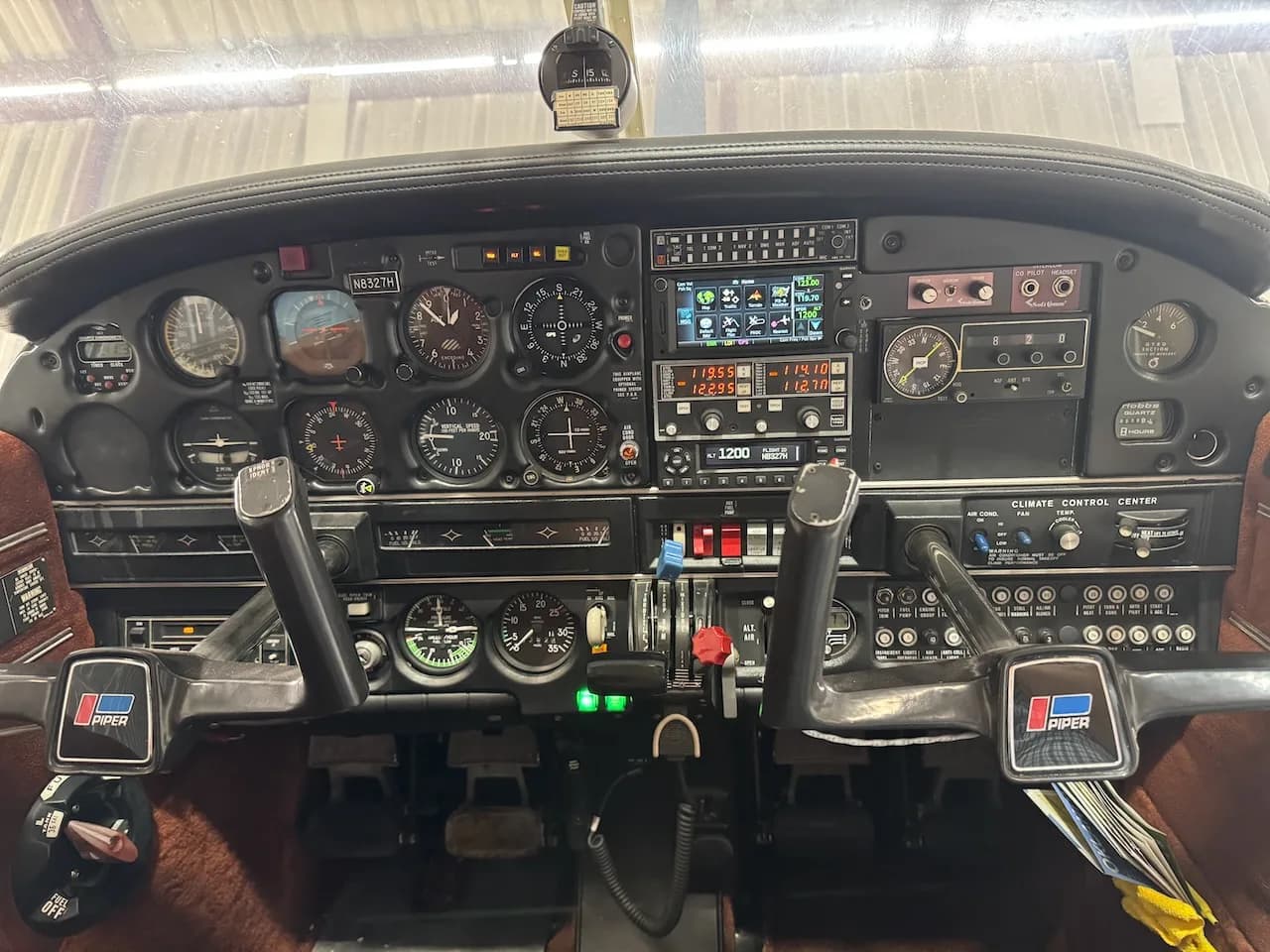 The cockpit of a Piper Arrow II aircraft, showing the instrument panel with analog gauges and a modern digital display.