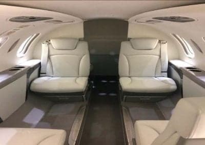 The aircraft's interior features white leather seats and a spacious cabin.