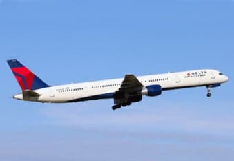 A Delta Boeing 757 taking off against a clear blue sky.