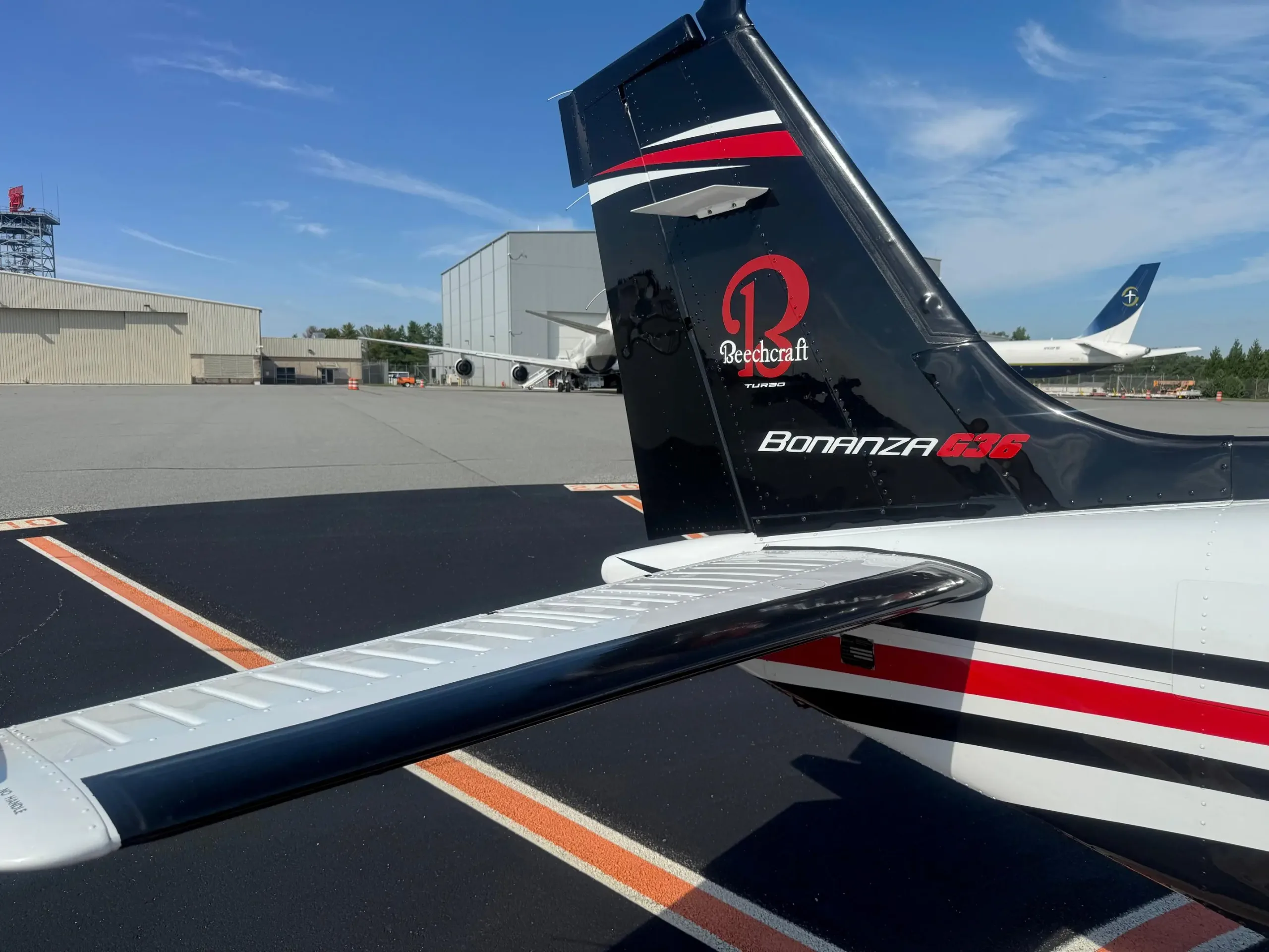 A close-up of the black tail of a Beechcraft Bonanza G36, featuring the Beechcraft logo and red and white stripes.