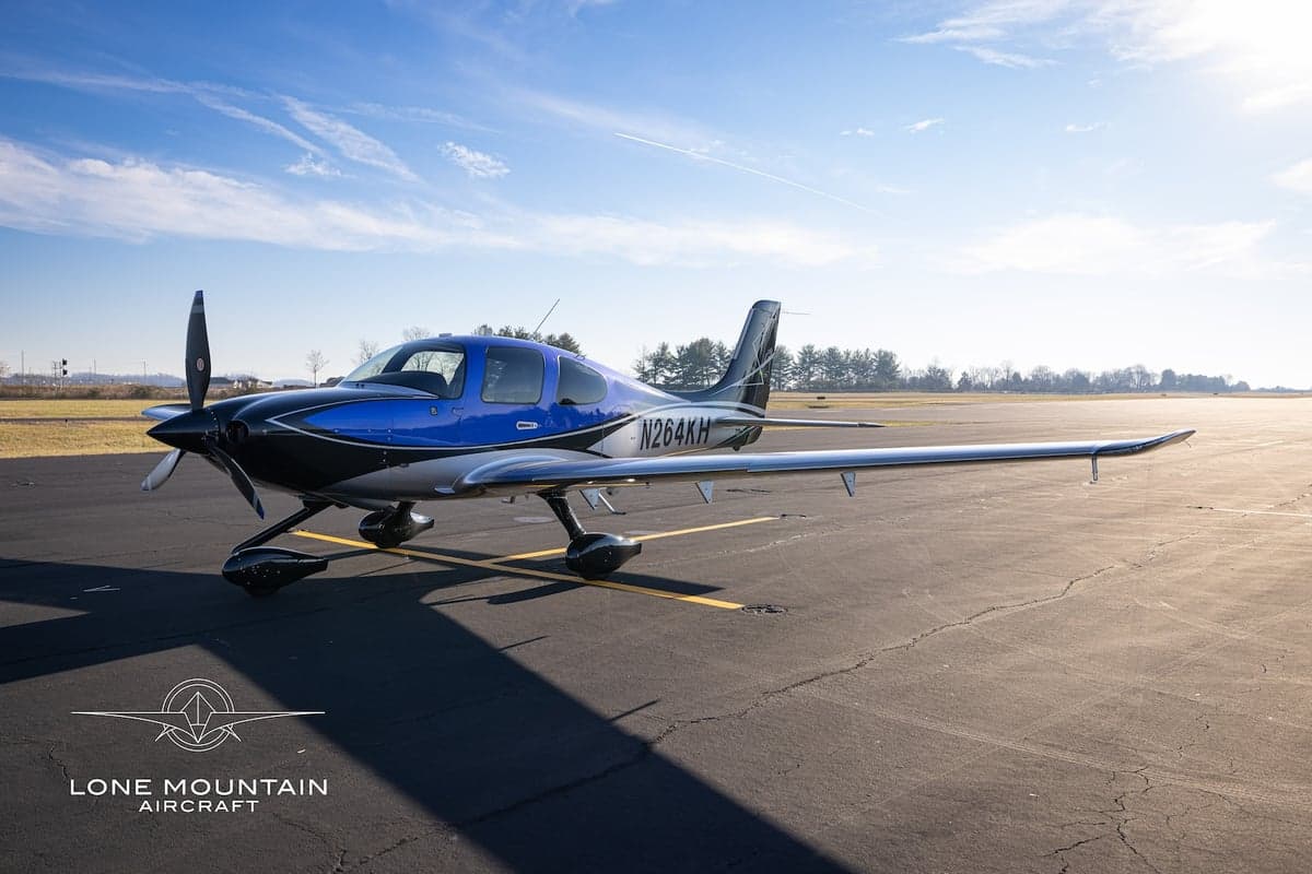 A Cirrus SR22T aircraft with registration N264KH parked on the tarmac in the sunlight.