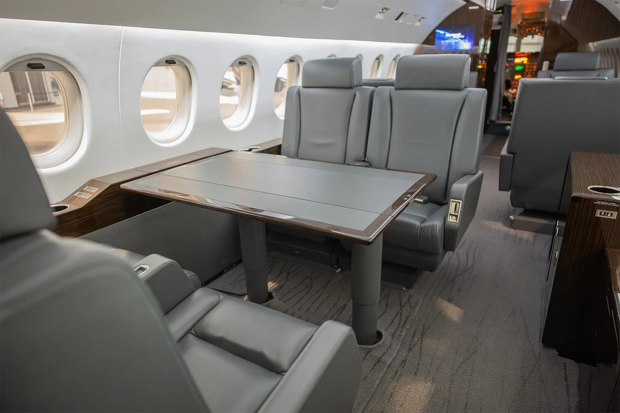 View of the aircraft interior with gray leather seats and a table.