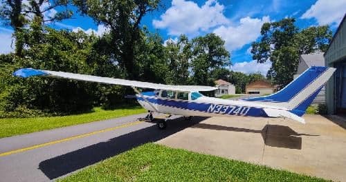 A Cessna 172 Skyhawk, registration N3374U, parked on a ramp with trees in the background.
