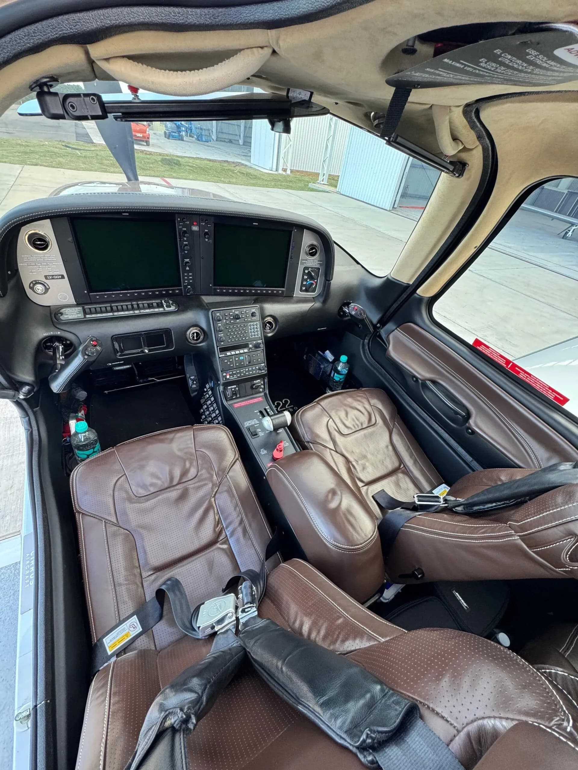 The cockpit and front brown leather seats of a Cirrus SR22T aircraft, showing the instrument panel.