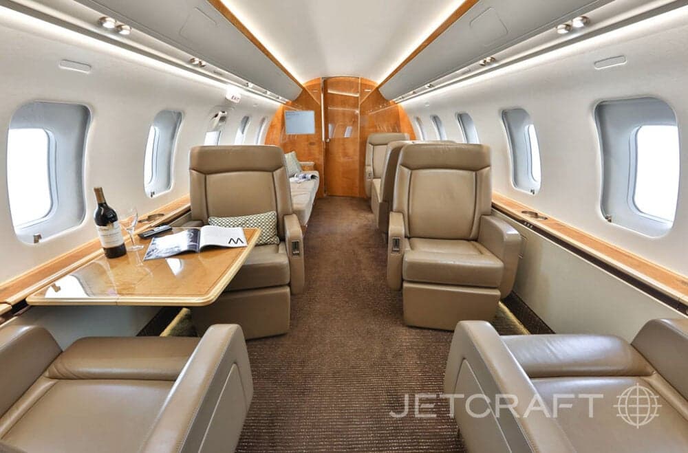 Aircraft interior with leather seats, table, and carpet.