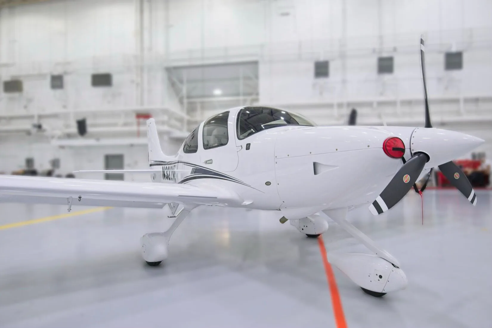 A close-up front three-quarter view of the propeller and nose of a white Cirrus SR22 aircraft, N322NE.