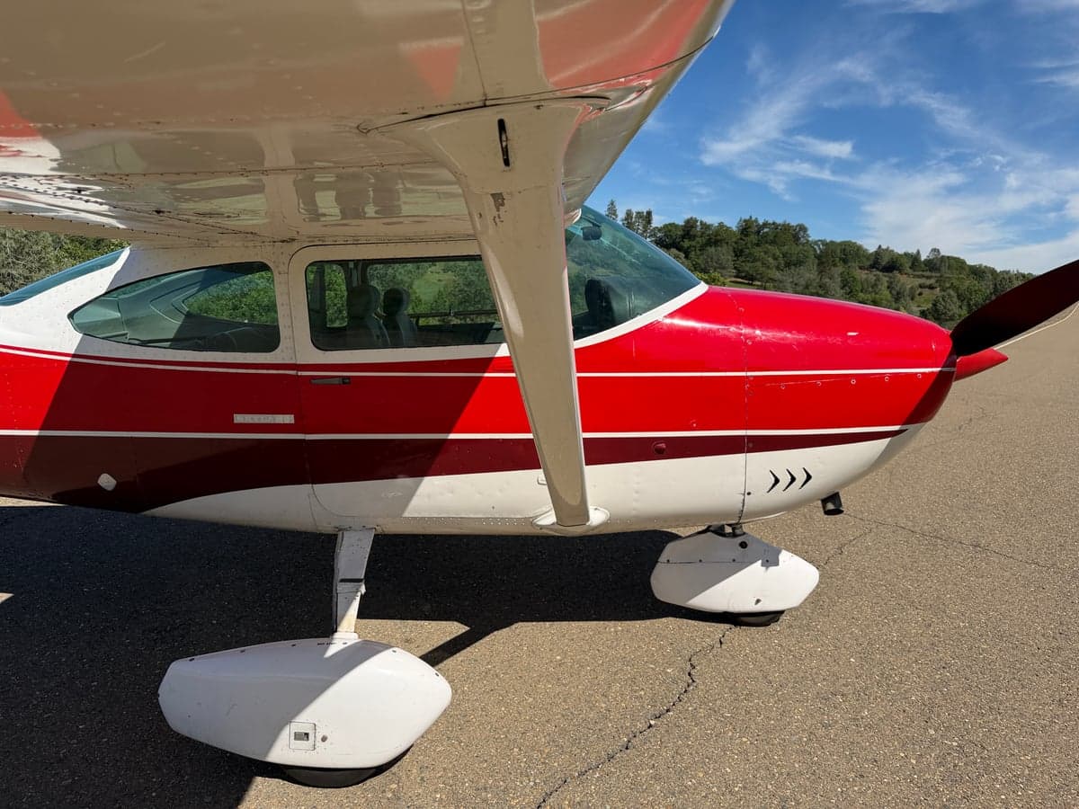 Close-up of the landing gear and lower fuselage of the red and white Cessna Skylane.
