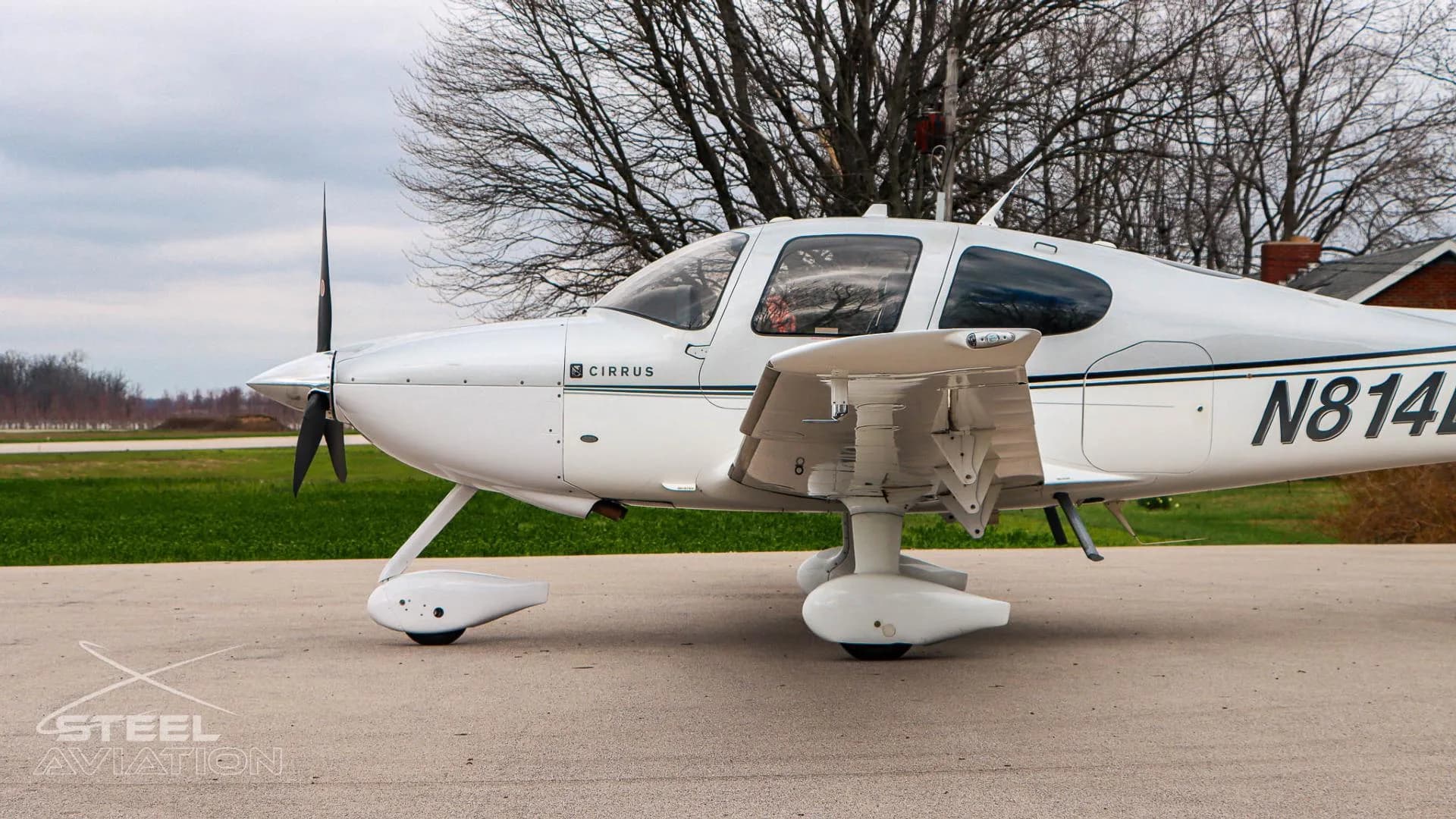A close-up side view of the white and silver Cirrus SR22 aircraft (N814LT) showing the fuselage, wing, and landing gear.