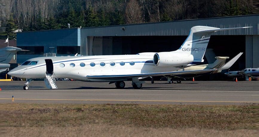 A white and silver Gulfstream G650ER parked on the tarmac with the boarding stairs down.