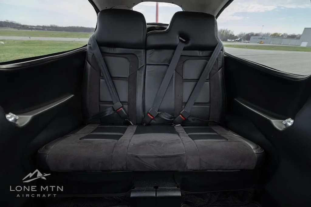 The black leather and suede rear seats of the aircraft cabin with seatbelts.