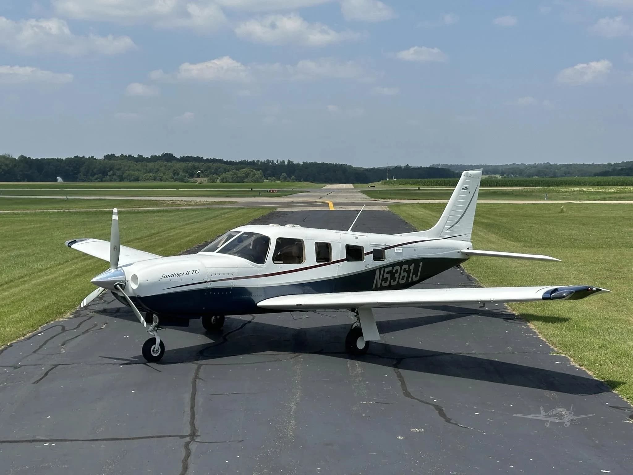 A three-quarter front view of the white and blue Piper Saratoga II TC (N5361J) on an airfield.