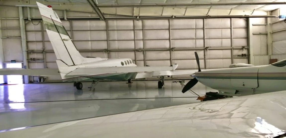 Two Cessna aircraft parked inside a hangar with a red ATV in the middle.
