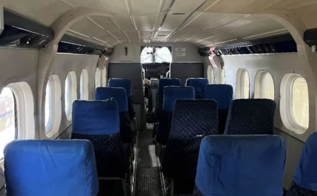 The interior cabin of an aircraft with blue seats and a view towards the cockpit.