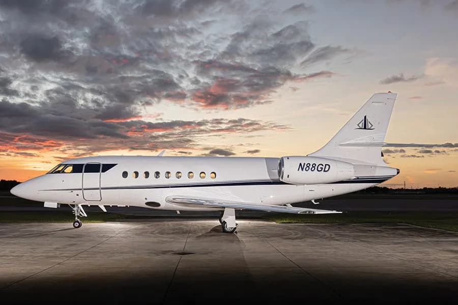 A white Dassault Falcon business jet with registration N88GD is parked on a tarmac at sunset.