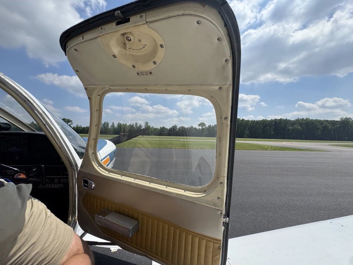 View from inside the aircraft, looking out the open door onto the runway.