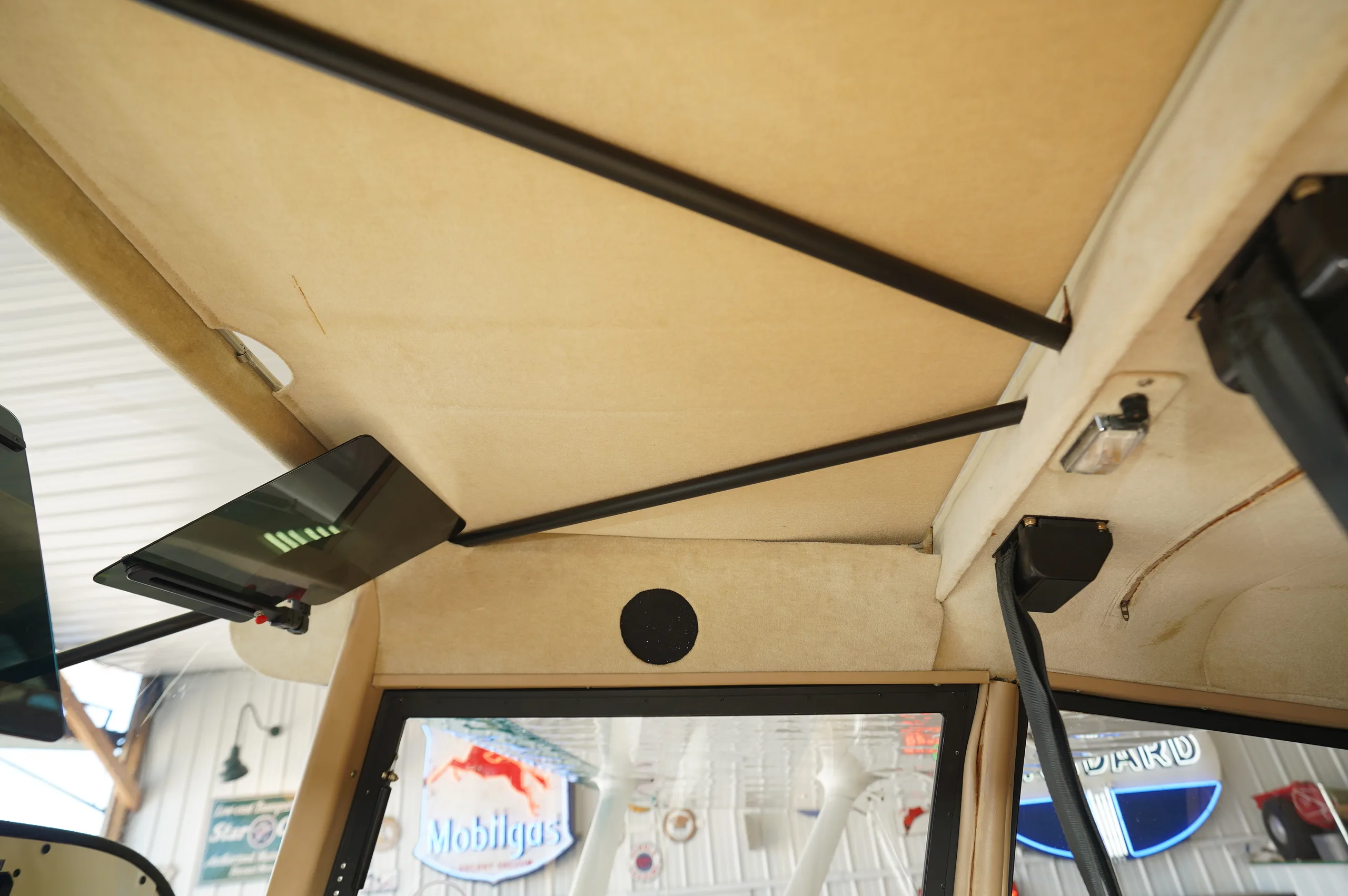 View of the tan fabric ceiling and structural bars inside the aircraft cabin.