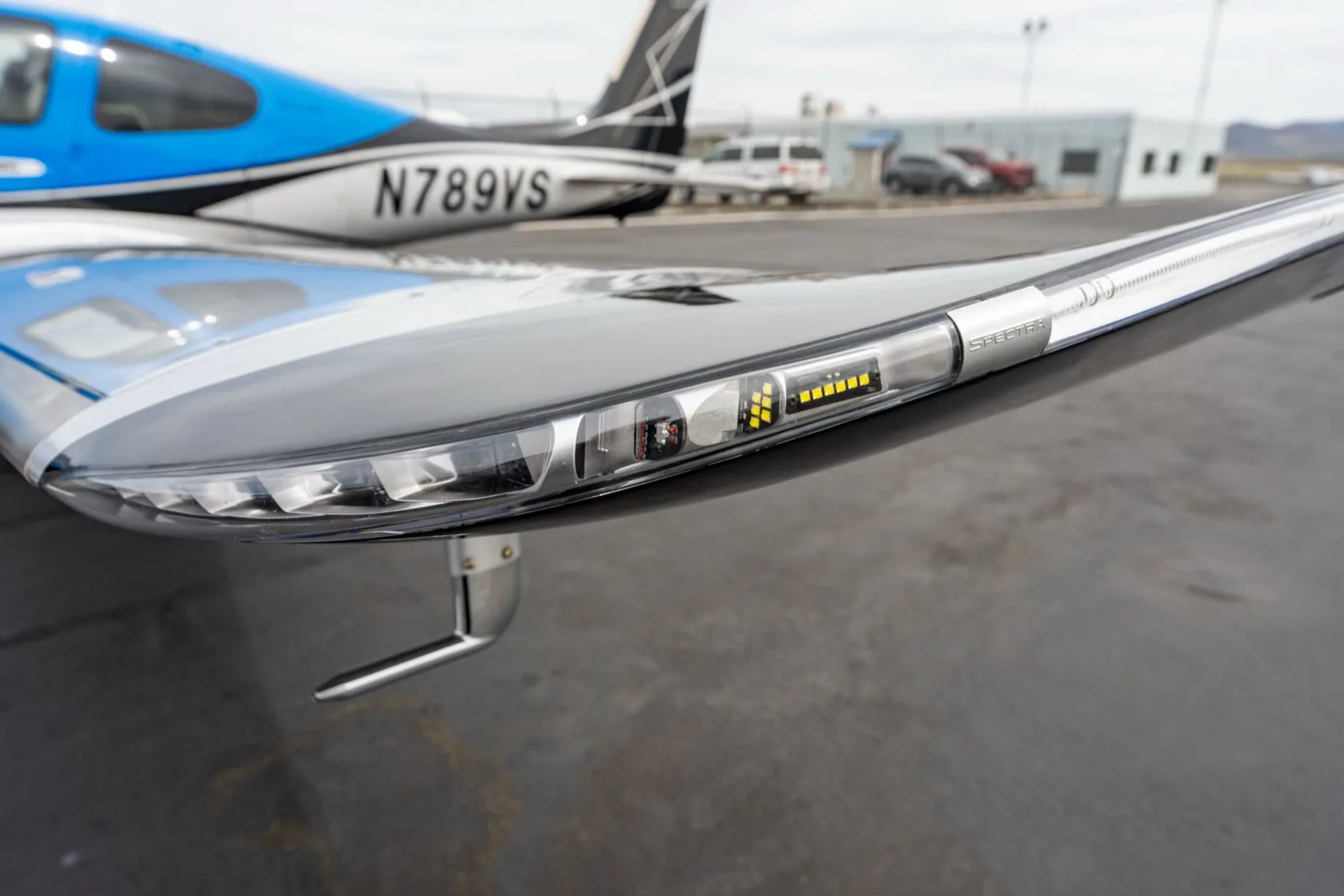 Close-up view of the wingtip light assembly on a black and silver aircraft wing.