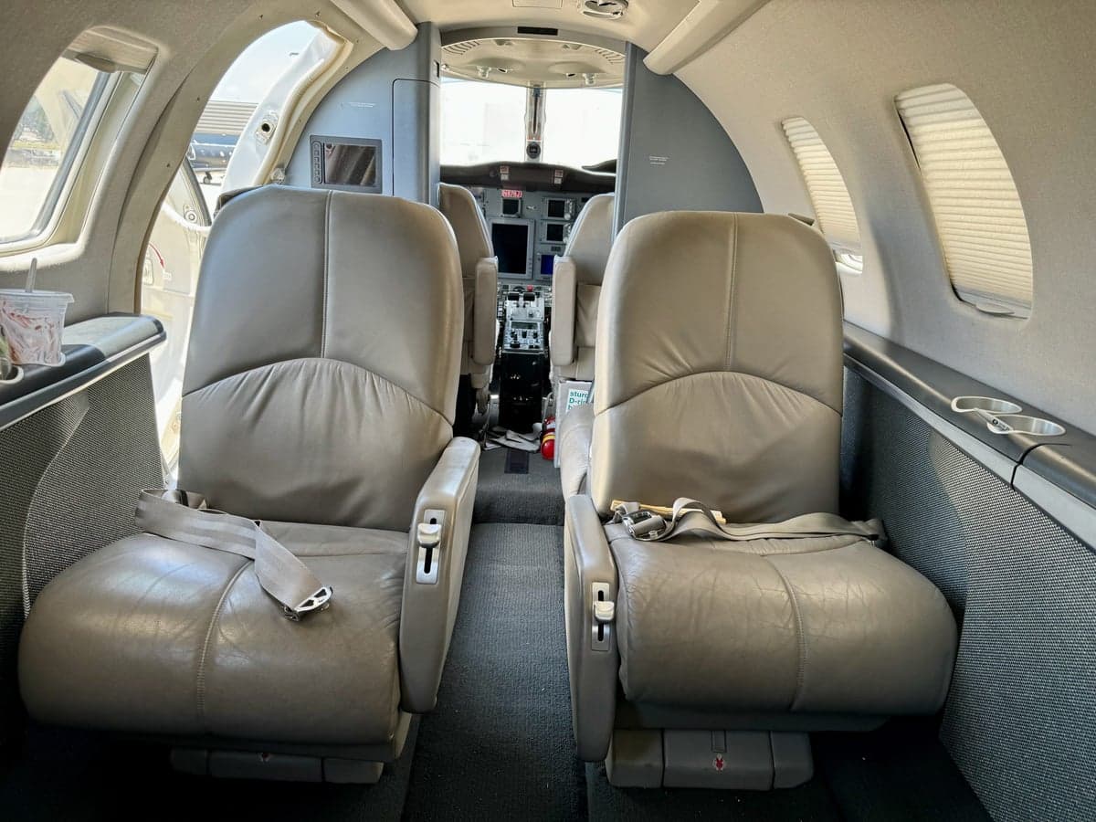 Aircraft cabin with leather seats and view of the cockpit.