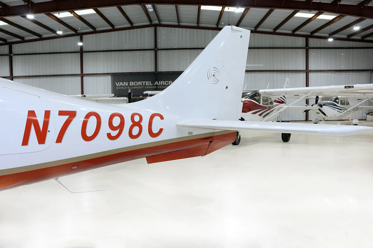 The tail section of a white and red Columbia 400 aircraft showing registration N7098C in a hangar.