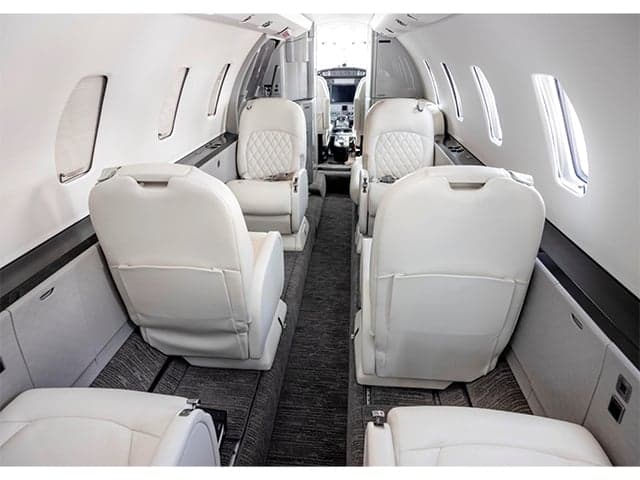 The interior of the aircraft features white leather seats and gray carpet.
