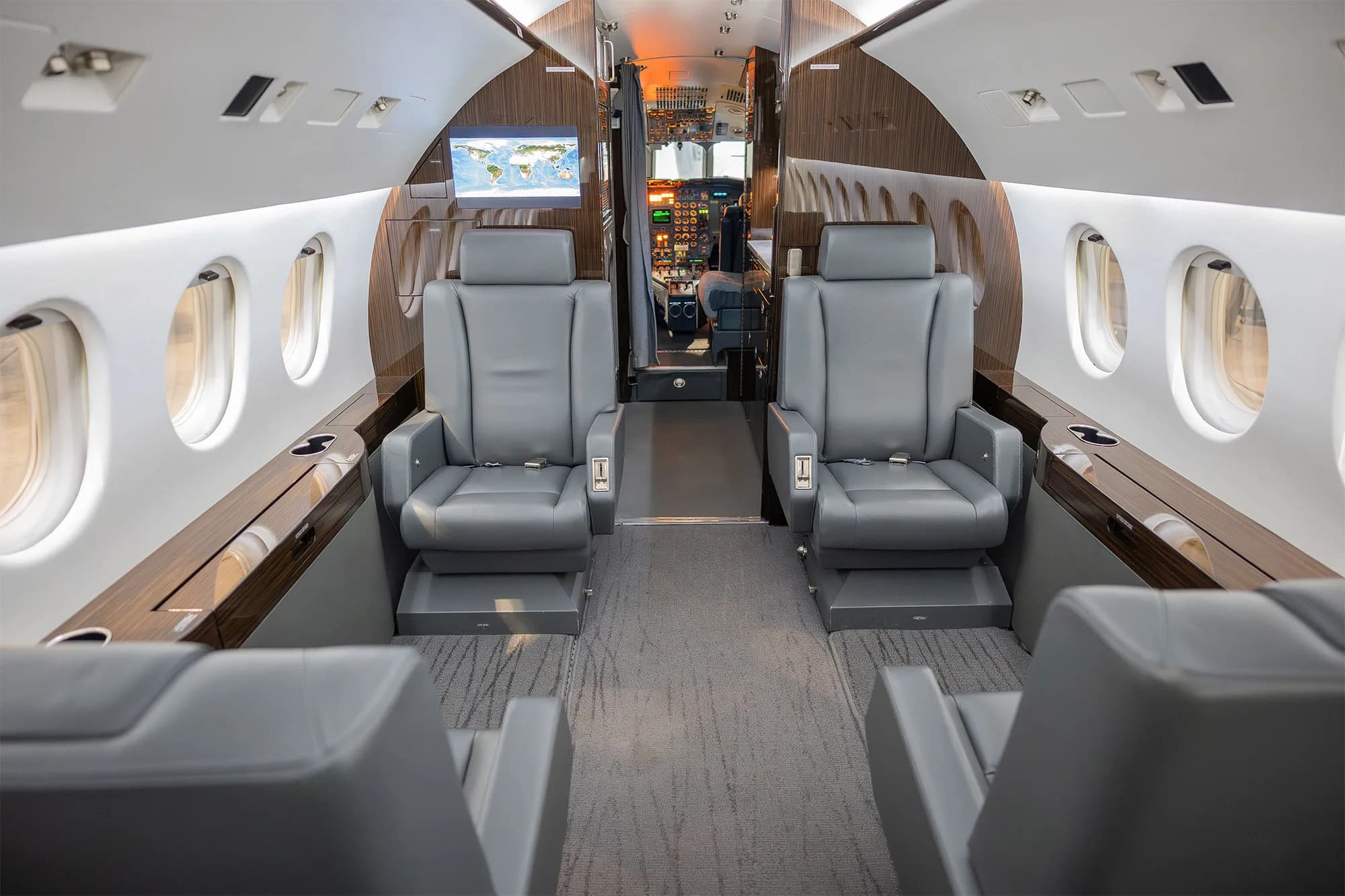 View of the aircraft interior with gray leather seats and wood trim.