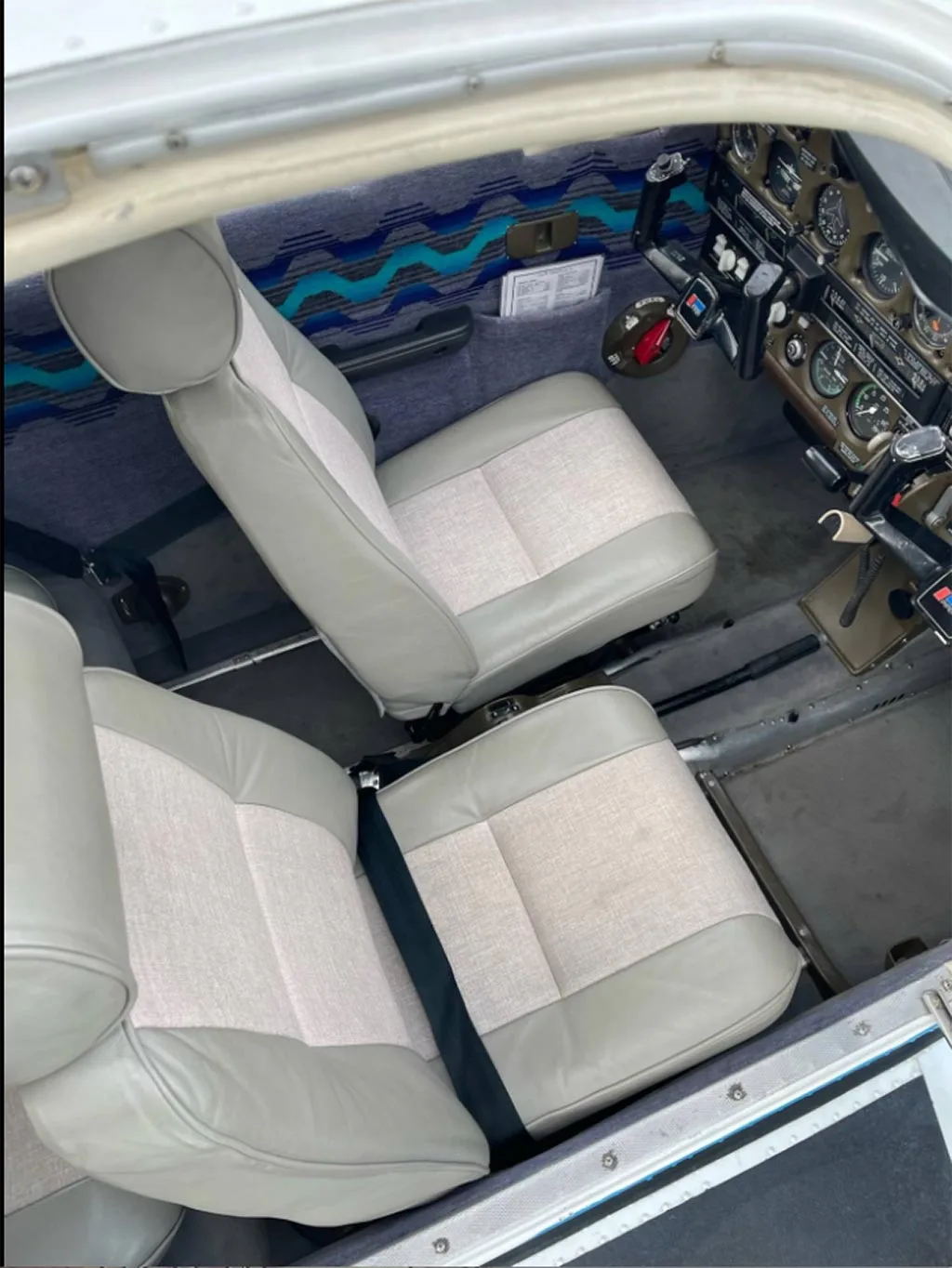 A view of the two front seats in the aircraft cabin, with a partial view of the cockpit instruments.