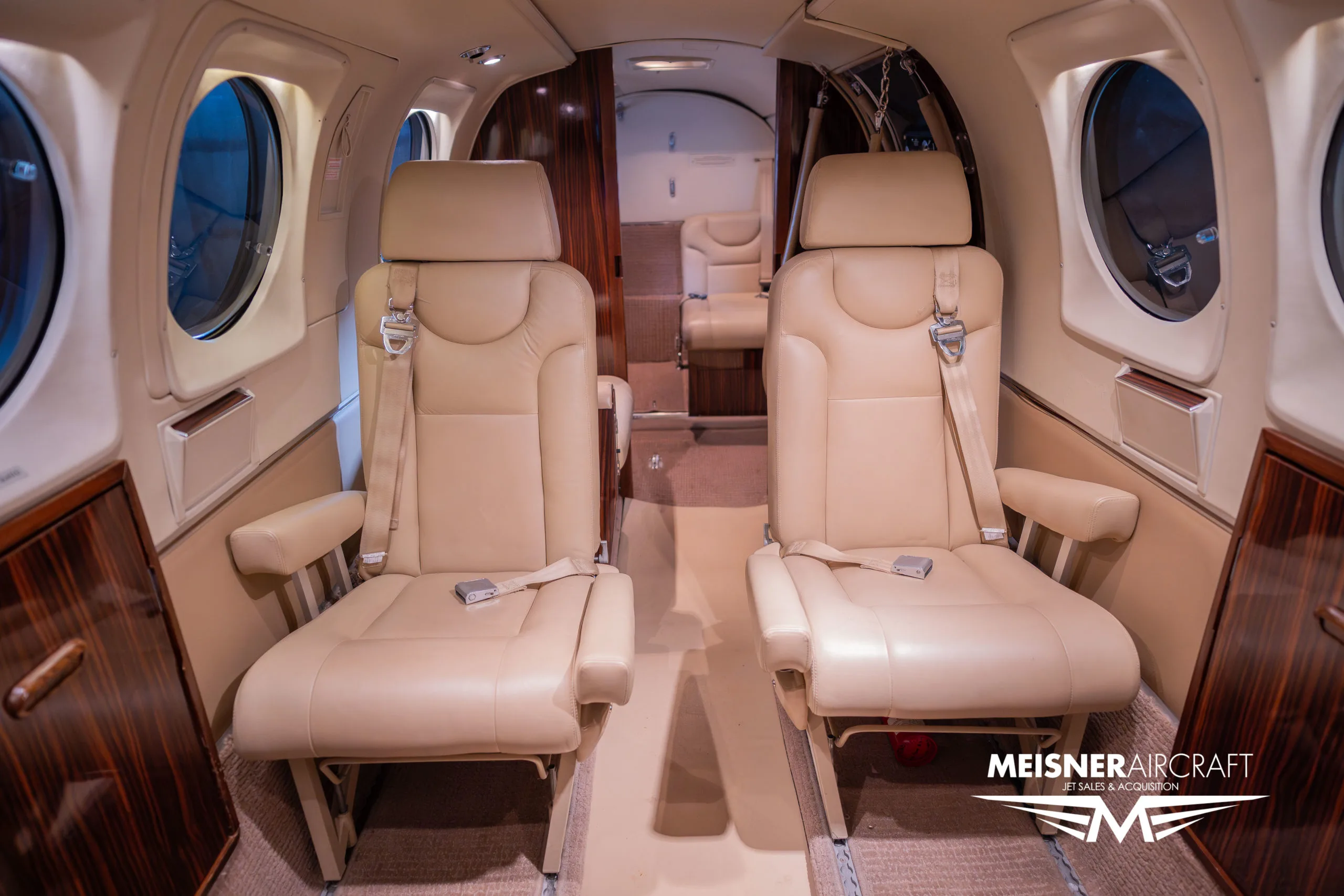 The beige leather interior cabin of a Beechcraft King Air, looking towards the rear seating area.