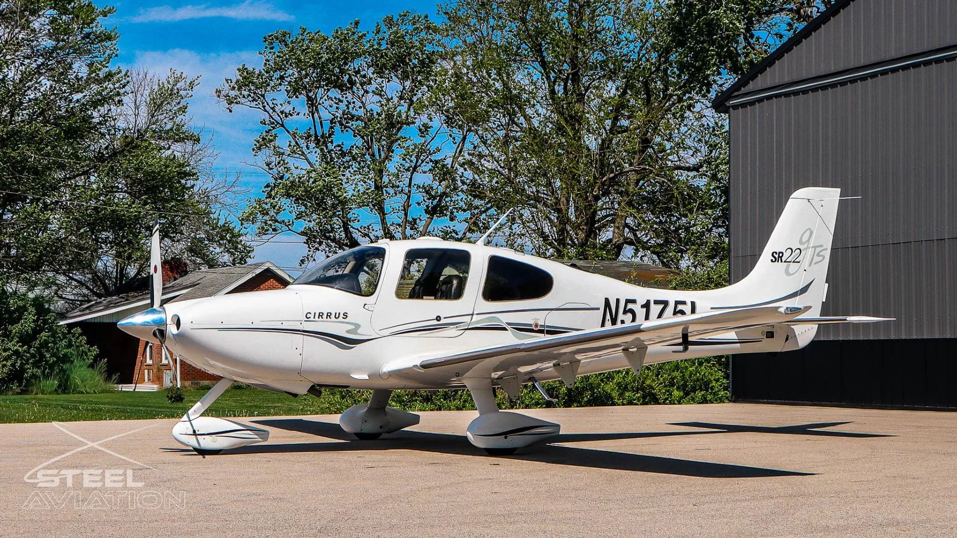 Left side view of a white Cirrus SR22 aircraft (N5175L) with black and grey stripes, parked on a sunny day.