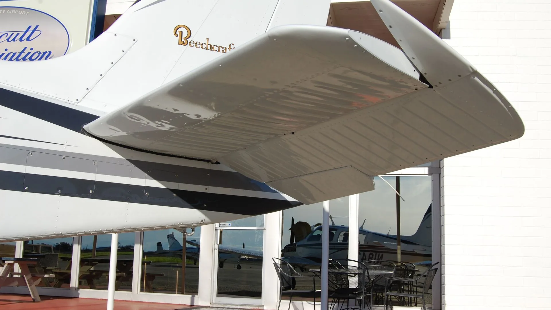Close-up of the tail of a Beechcraft Bonanza, showing the Beechcraft logo and horizontal stabilizer.