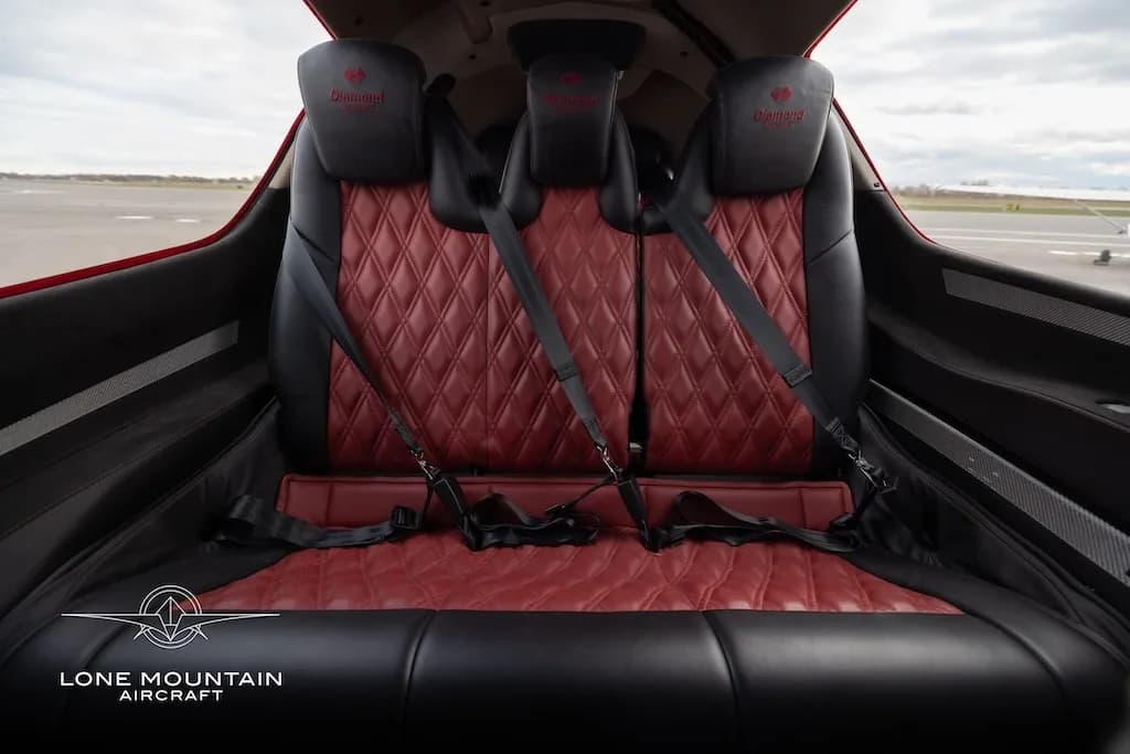 A wider view of the red quilted leather and black rear passenger seats in the Diamond DA62 cabin.