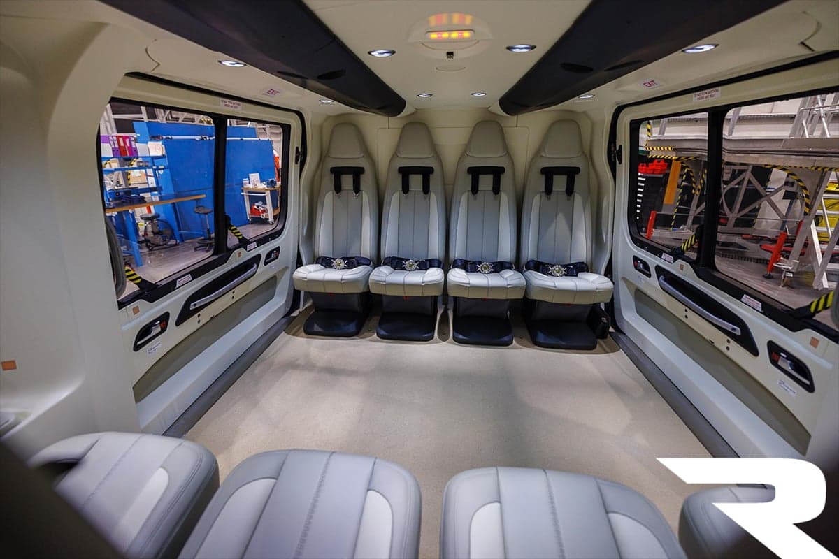 The interior cabin of an Airbus H160 helicopter, showing two rows of light grey passenger seats.