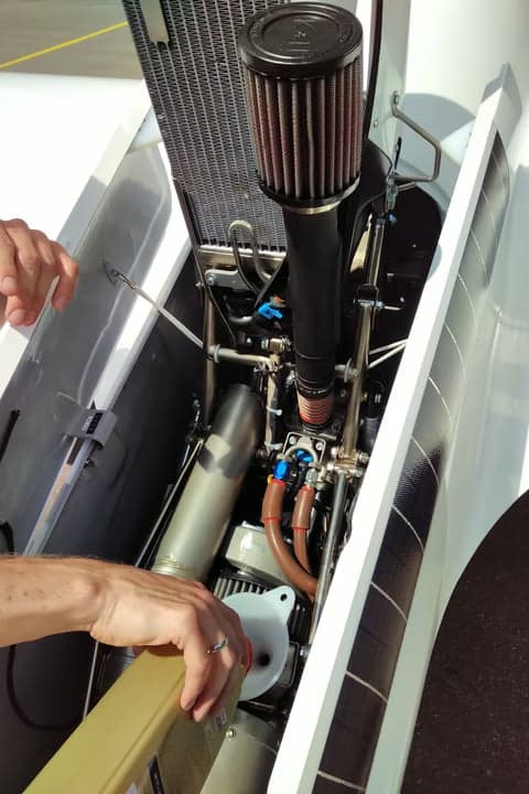 A glider with open cockpit being loaded into a trailer.