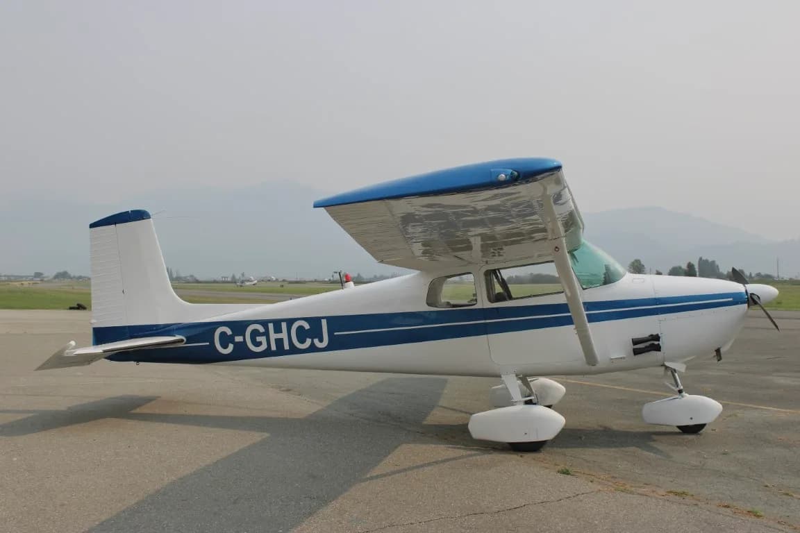 Side view of a Cessna 172 with blue stripe parked on the tarmac.