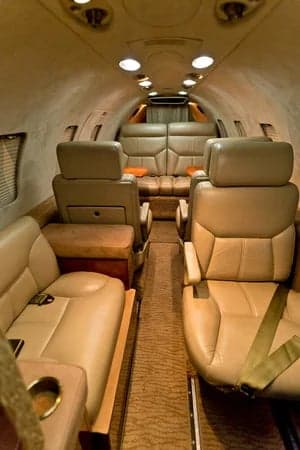 A view of the interior cabin of the aircraft, showing the seating arrangement and tan leather seats.