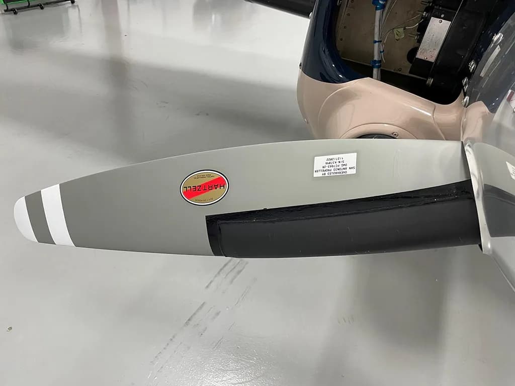A close-up of a gray propeller blade with a "HARTZELL" logo and white stripes.